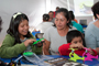 Personas de todas las edades participan en las actividades de la AMC. En la imagen, padres de familia y niños se divierten y aprenden en el Taller de Robótica.