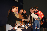 Una maestra de educación primaria recibe su diploma de La Ciencia en tu Escuela tras haber concluido satisfactoriamente el curso, que incluye clases y actividades a lo largo de 22 sábados, presentación de tareas y aprobación de exámenes.