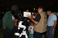 Fidel Torres, de la Sociedad Astronómica Nibiru de la Facultad de Ciencias de la UNAM, explica a una familia lo que a través de la lente del telescopio se puede observar en el cielo.